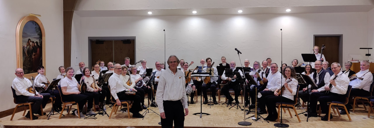 Conductor, Lon Hendricks, stands in front of the stage filled with mandolin players at Saint Anthony Park Lutheran Church in Saint Paul, Minnesota.