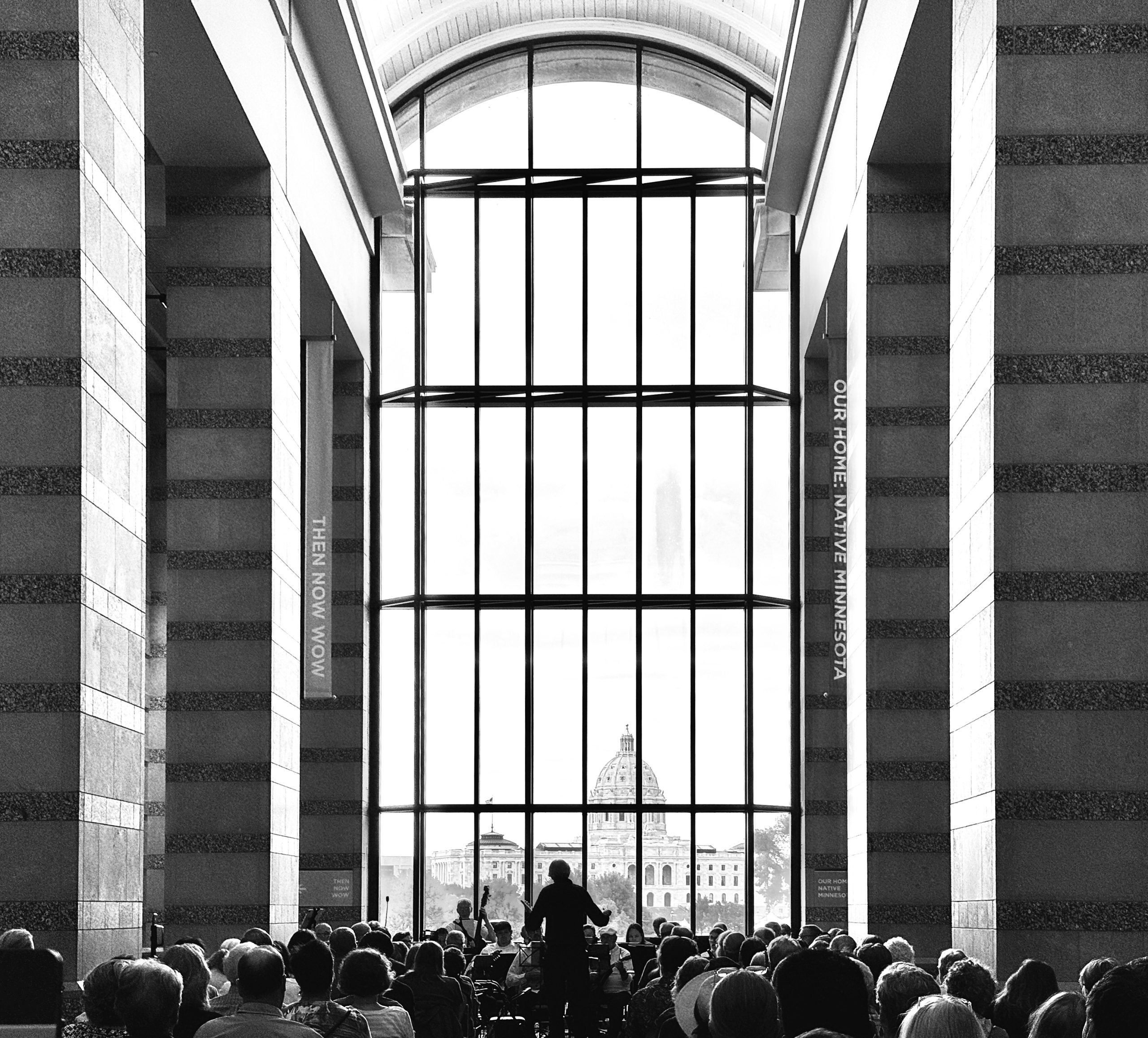 Mandolin orchestra performs in the atrium of the Minnesota History Center with the state capital in the background.